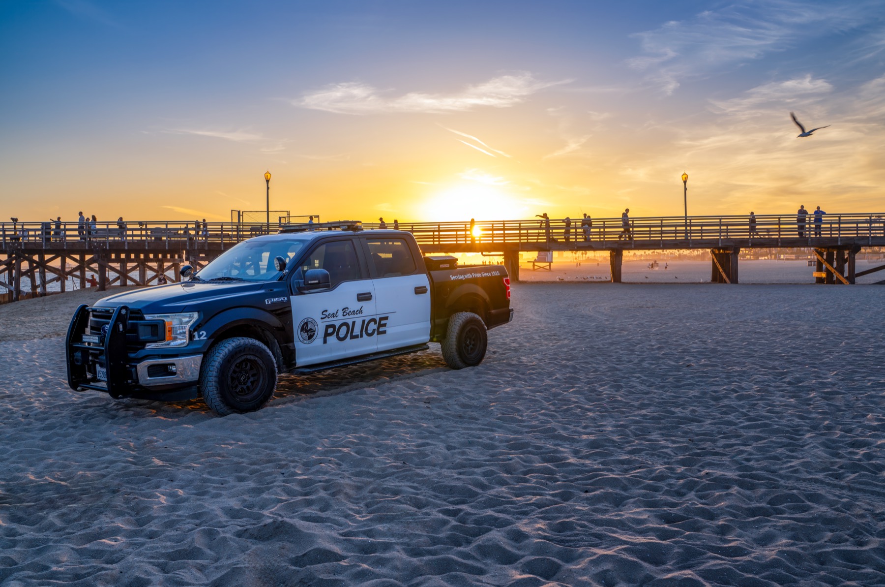 Seal Beach Police truck on the sand near the pier at sunset